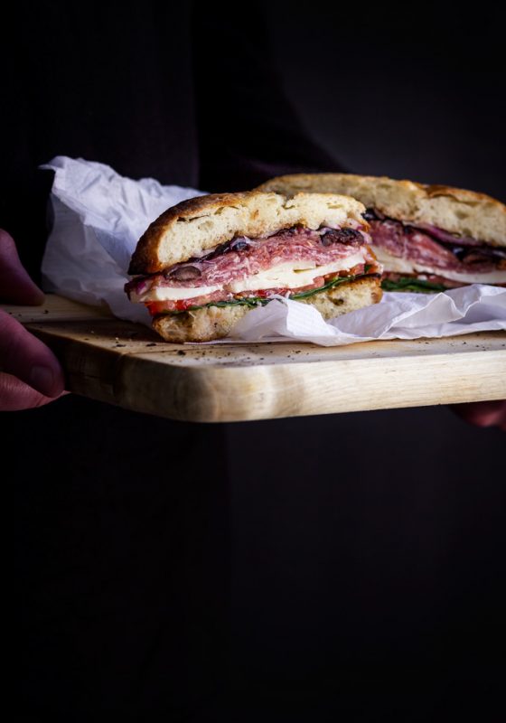 This easy to make muffuletta sandwich recipe is a must for the Italian antipasto lovers. It is made of muffuletta bread infused with fragrant olive oil dressing, layers of gorgeous Italian cold cuts and cheeses. Make this Italian sandwich a day ahead to save some time because this New Orleans pride gets better as it sits. #muffuletta #sandwich #italiansandwich