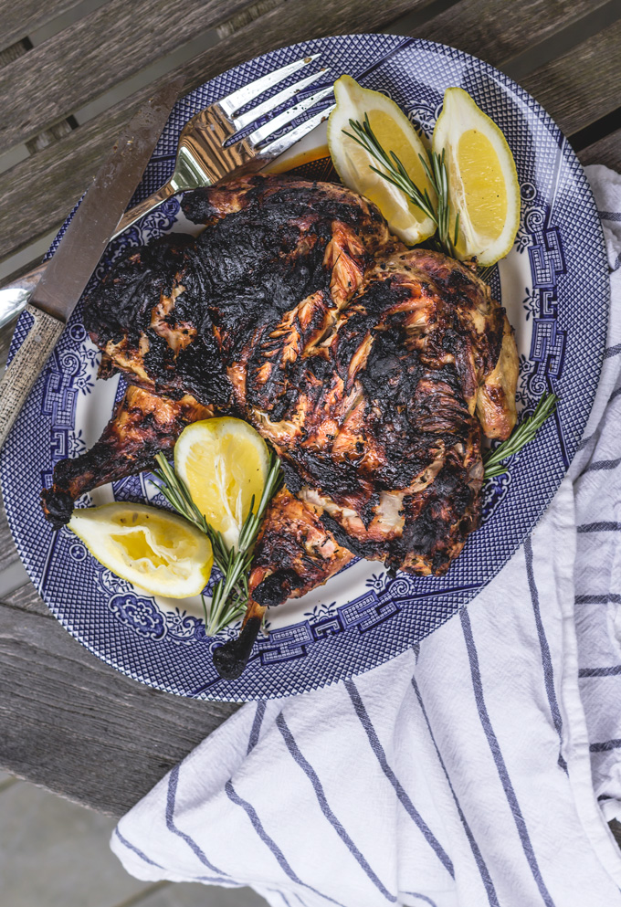 Tuscan style grilled lemon chicken recipe. Very juicy and tender marinated whole grilled chicken with a beautiful crispy skin. The meat easily comes off the bones and melts in your mouth. The secret is in the lemon chicken marinade. Such simple and straightforward marinade yields unbelievably moist and flavorful grilled chicken. To me, the juicy meat and crispy skin is always a winner in grilled chicken recipes. #chicken #wholechicken #grilledchicken #chickenmarinade